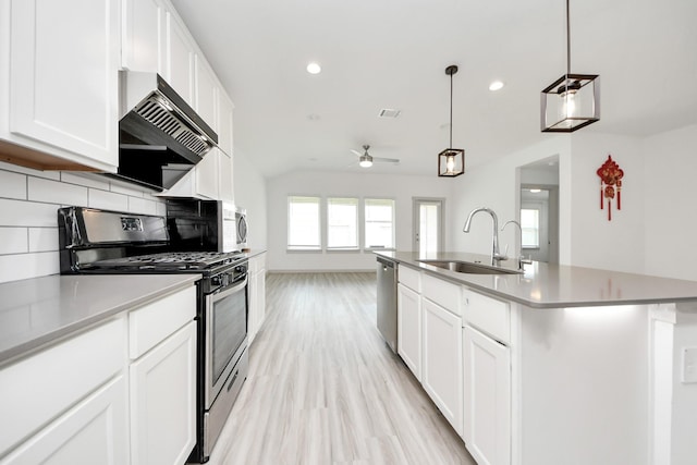 kitchen with ceiling fan, appliances with stainless steel finishes, a sink, light wood-style flooring, and tasteful backsplash