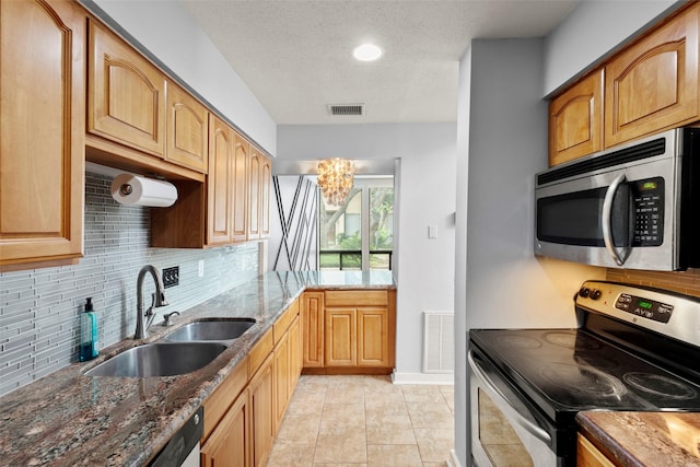 kitchen with a sink, decorative backsplash, stainless steel appliances, and visible vents