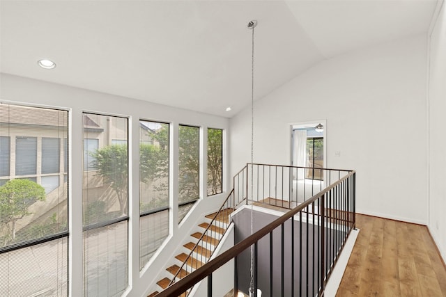 stairway featuring vaulted ceiling, recessed lighting, wood finished floors, and a wealth of natural light