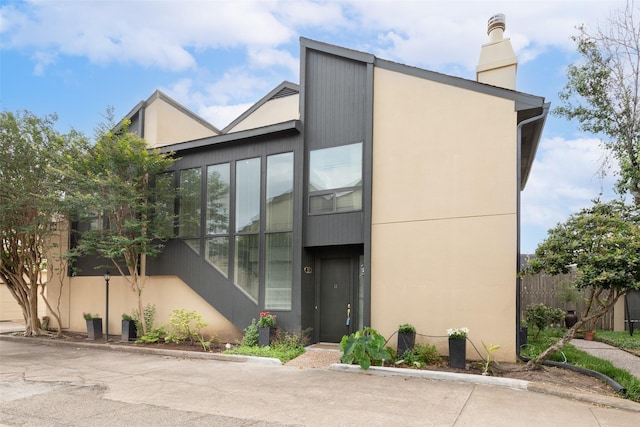 exterior space with fence, a chimney, and stucco siding