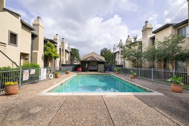 community pool featuring a residential view, fence, and a patio area