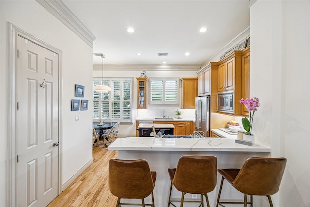 kitchen featuring recessed lighting, a peninsula, appliances with stainless steel finishes, and a kitchen bar
