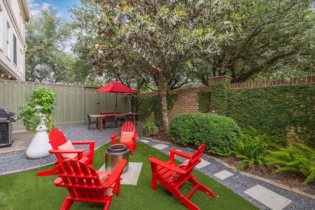 view of patio featuring area for grilling, a fenced backyard, and an outdoor fire pit
