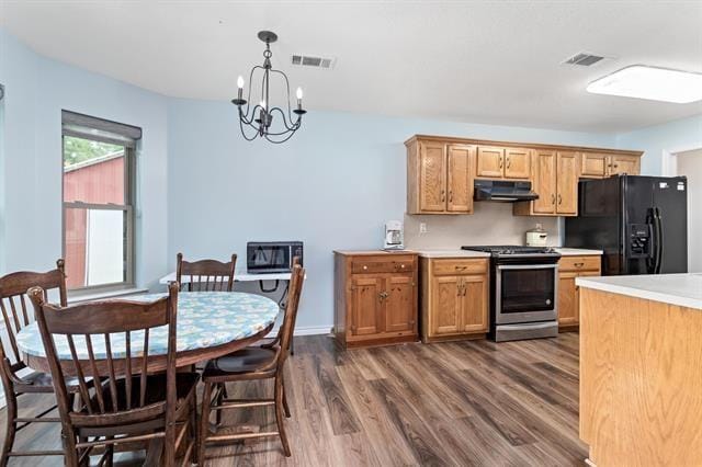kitchen with dark wood-style flooring, an inviting chandelier, light countertops, under cabinet range hood, and black appliances