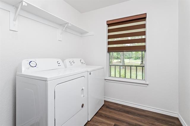 clothes washing area featuring laundry area, baseboards, dark wood-type flooring, and washing machine and clothes dryer