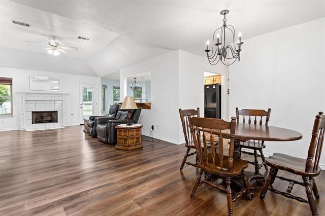 dining area featuring baseboards, ceiling fan with notable chandelier, dark wood-style floors, and visible vents