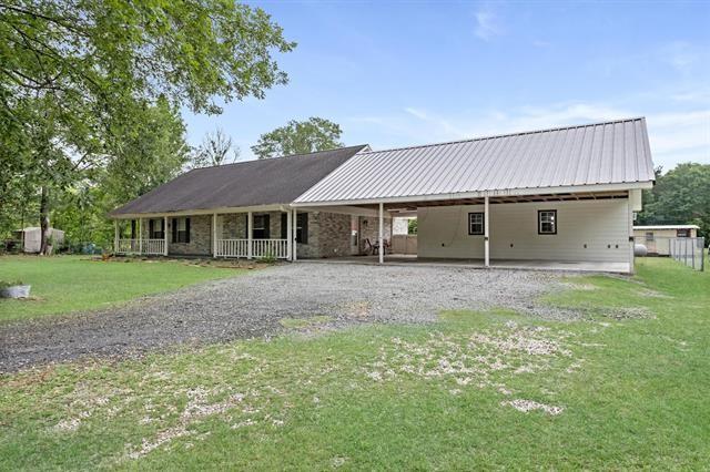 rear view of house featuring a carport, a yard, driveway, and metal roof