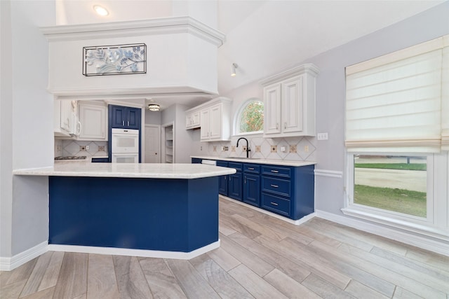 13414 Autumn Valley Dr, Cypress, TX 77429 - kitchen with blue cabinets, a sink, white double oven, a peninsula, and light countertops