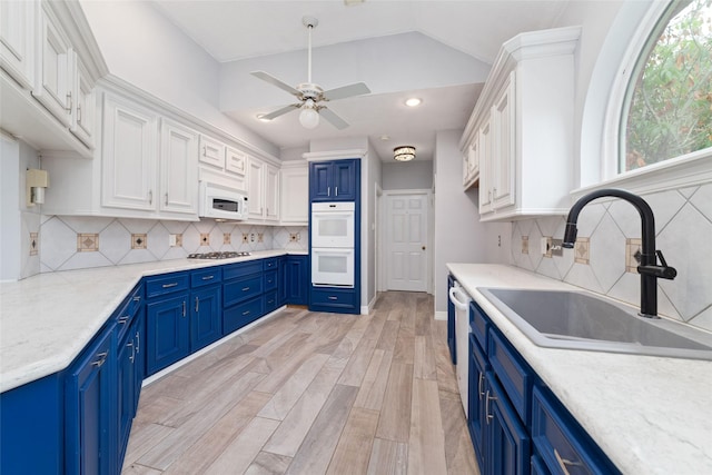 13414 Autumn Valley Dr, Cypress, TX 77429 - kitchen featuring blue cabinetry, white appliances, a sink, white cabinets, and lofted ceiling