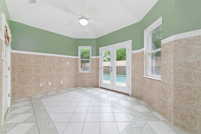 13414 Autumn Valley Dr, Cypress, TX 77429 - tiled empty room featuring french doors, tile walls, a ceiling fan, wainscoting, and lofted ceiling