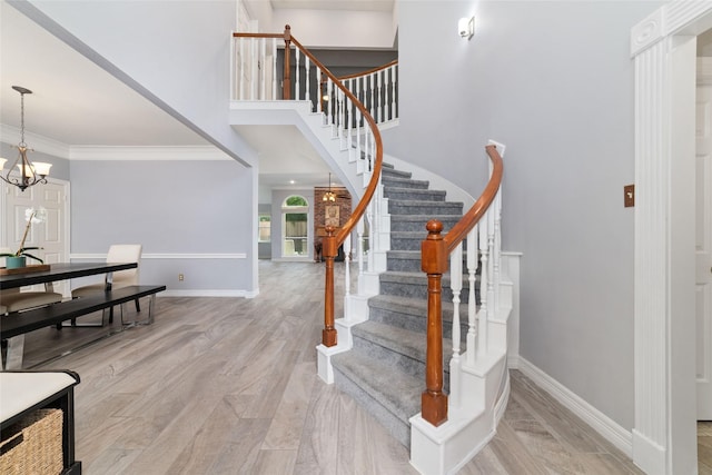 13414 Autumn Valley Dr, Cypress, TX 77429 - stairway featuring baseboards, a chandelier, wood finished floors, ornamental molding, and a high ceiling