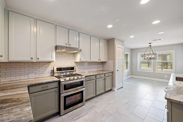 kitchen with gray cabinets, double oven range, visible vents, tasteful backsplash, and under cabinet range hood
