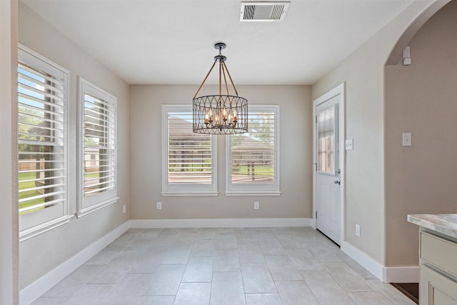 unfurnished dining area with visible vents, arched walkways, baseboards, an inviting chandelier, and light tile patterned flooring