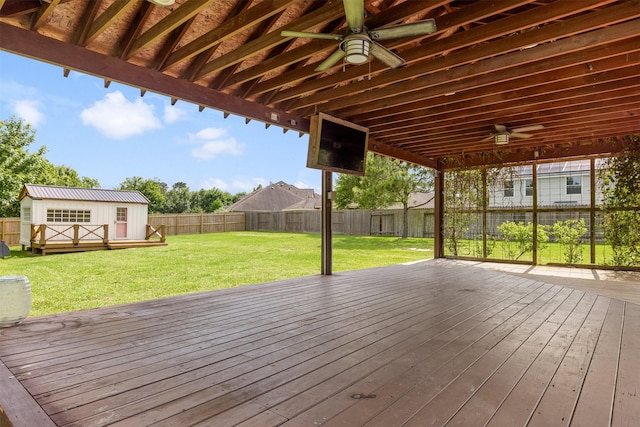 wooden deck featuring ceiling fan, an outbuilding, a fenced backyard, a shed, and a yard