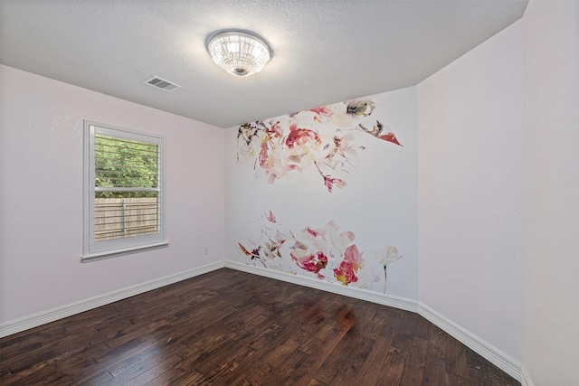 empty room featuring visible vents, dark wood finished floors, and baseboards