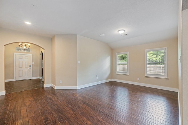 spare room with dark wood-style flooring, arched walkways, baseboards, and visible vents