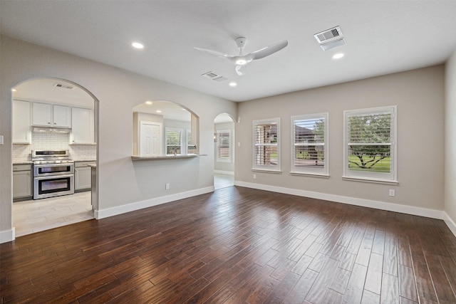 unfurnished living room with a wealth of natural light, a ceiling fan, and visible vents