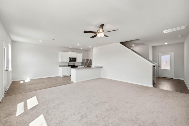 unfurnished living room with baseboards, ceiling fan, light carpet, and visible vents