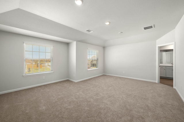 unfurnished bedroom with visible vents, carpet, lofted ceiling, and baseboards