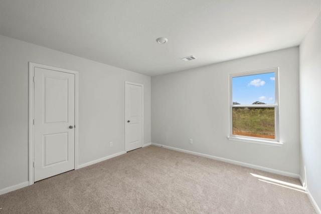 unfurnished bedroom with carpet floors, baseboards, and visible vents