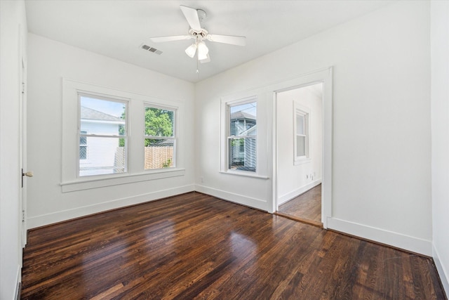 unfurnished room with baseboards, visible vents, dark wood-style floors, and ceiling fan