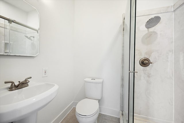 full bathroom featuring toilet, baseboards, a sink, and a stall shower