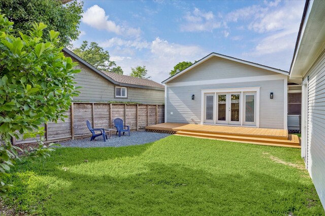 back of property featuring fence, a lawn, and a deck