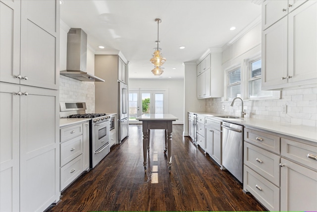 kitchen with light countertops, wall chimney exhaust hood, tasteful backsplash, a sink, and stainless steel appliances