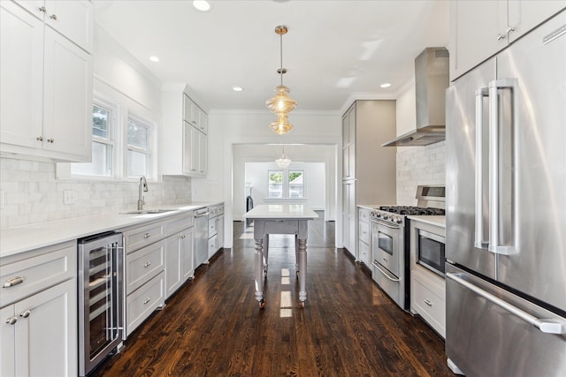kitchen featuring ornamental molding, wine cooler, wall chimney exhaust hood, a sink, and appliances with stainless steel finishes