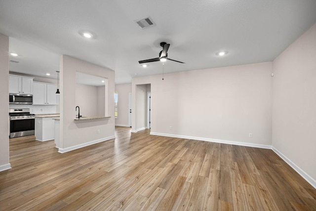 3031 Sunmoon Ln, Katy, TX 77493 - unfurnished living room featuring visible vents, a sink, light wood-style floors, and ceiling fan