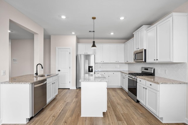 3031 Sunmoon Ln, Katy, TX 77493 - kitchen featuring appliances with stainless steel finishes, a sink, white cabinetry, tasteful backsplash, and a kitchen island