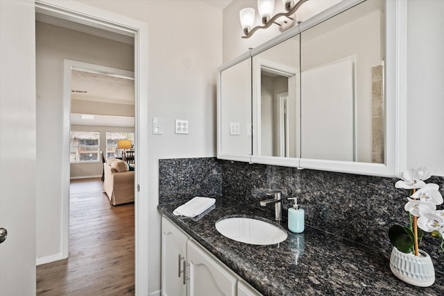 bathroom featuring vanity, tasteful backsplash, baseboards, and wood finished floors