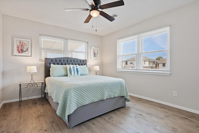 bedroom with baseboards, ceiling fan, wood finished floors, and visible vents