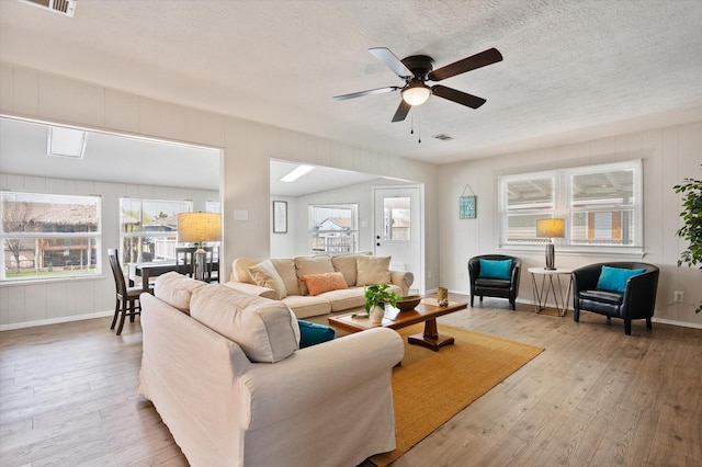 living room featuring a textured ceiling, ceiling fan, a wealth of natural light, and hardwood / wood-style floors