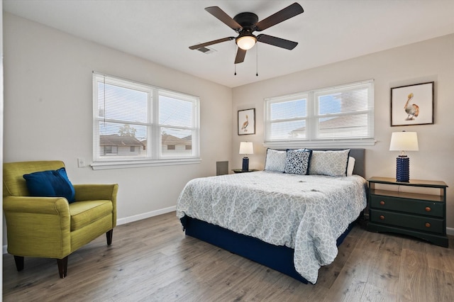 bedroom with a ceiling fan, baseboards, multiple windows, and wood finished floors