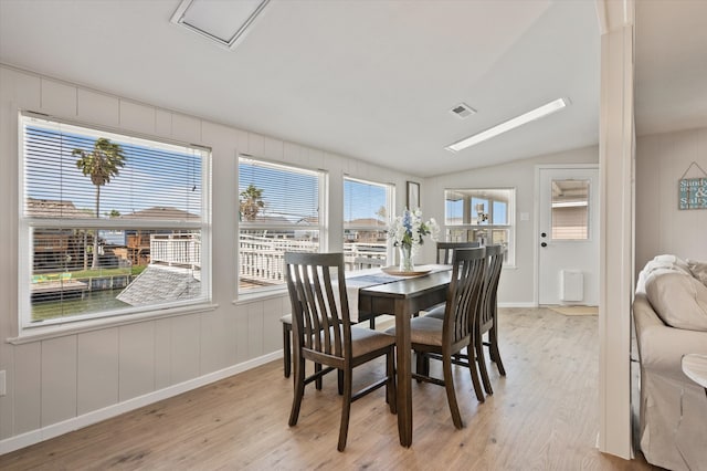 dining area with baseboards, vaulted ceiling, visible vents, and light wood-type flooring
