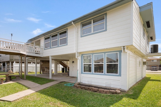 back of house with a wooden deck, cooling unit, a patio area, a yard, and a carport