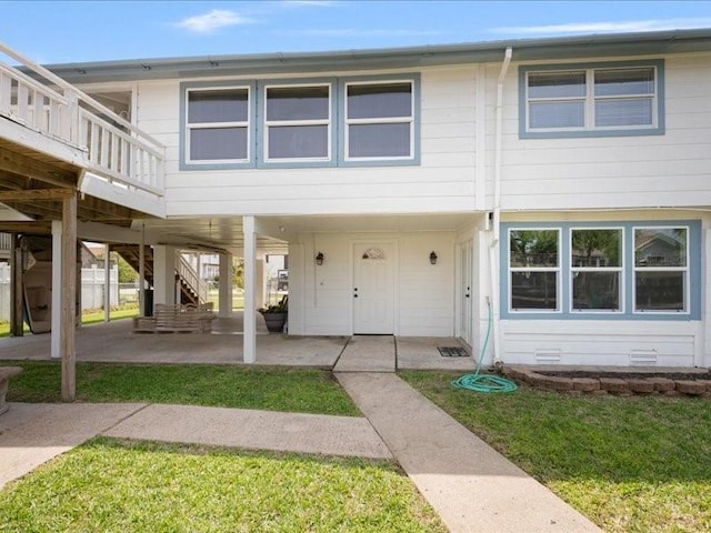 view of front of house with a front yard, a deck, a patio, stairs, and a carport