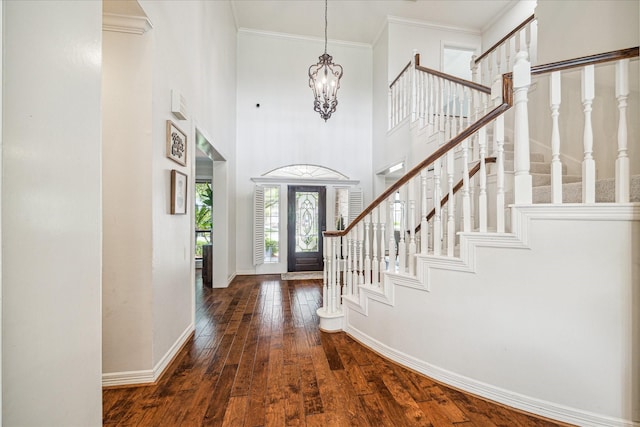 foyer with hardwood / wood-style flooring, ornamental molding, a towering ceiling, stairway, and baseboards
