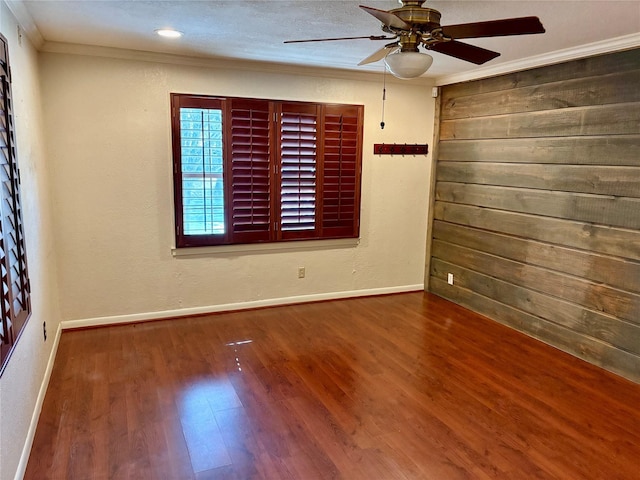 spare room with baseboards, ornamental molding, ceiling fan, and wood finished floors