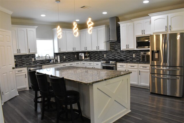 kitchen with wall chimney exhaust hood, white cabinets, and stainless steel appliances
