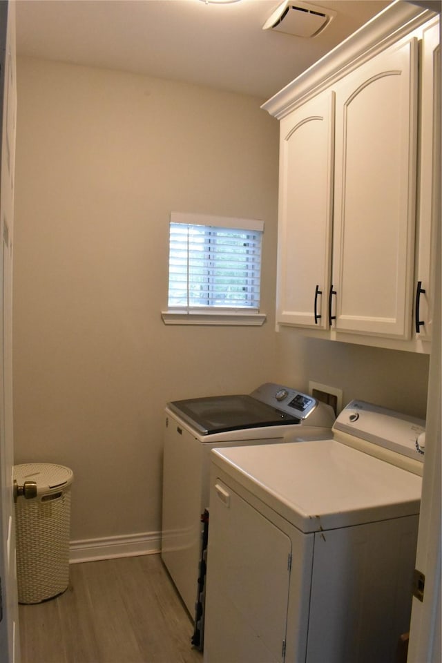 laundry room with visible vents, wood finished floors, cabinet space, baseboards, and washer and clothes dryer