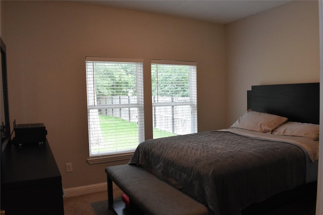 carpeted bedroom featuring baseboards and multiple windows