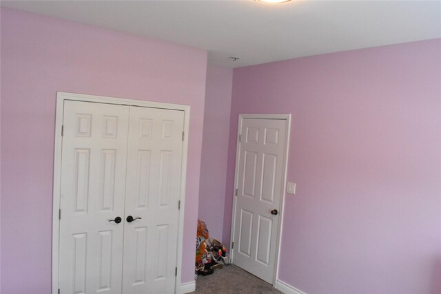 carpeted bedroom featuring baseboards and a closet