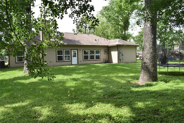 back of house featuring a lawn, central AC, and a trampoline