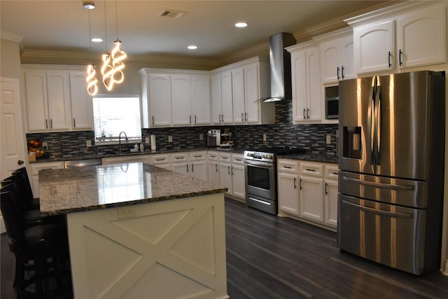 kitchen featuring wall chimney range hood, visible vents, crown molding, a sink, and stainless steel appliances
