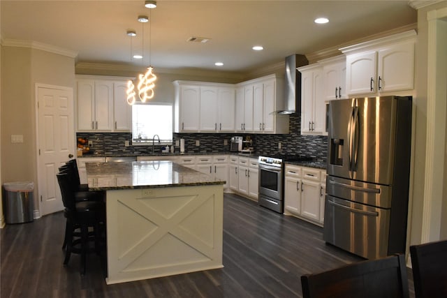 kitchen featuring decorative backsplash, wall chimney exhaust hood, white cabinets, a sink, and appliances with stainless steel finishes