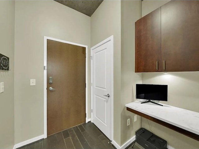 office area with baseboards, dark wood-style flooring, and built in desk