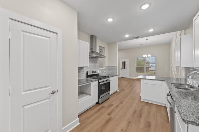 12341 N Chestnut Hills Dr, Conroe, TX 77303 - kitchen featuring light wood-type flooring, wall chimney exhaust hood, white cabinets, a sink, and appliances with stainless steel finishes
