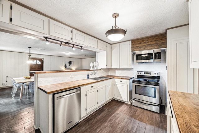 1602 Libbey Dr, Houston, TX 77018 - kitchen with butcher block countertops, stainless steel appliances, a sink, dark wood-style floors, and a textured ceiling